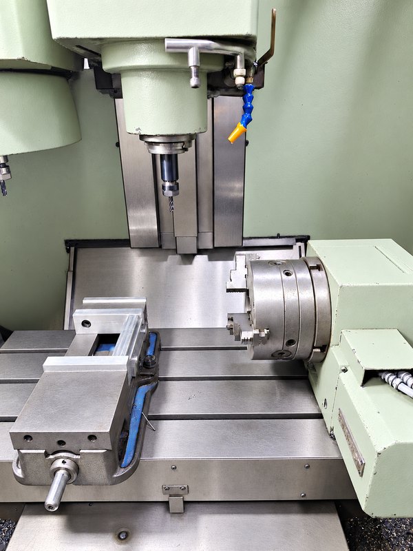 4-axis machining center with a rotary table and vise on the machine bed