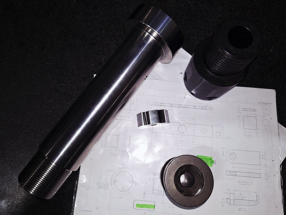 Machined parts laid on an engineering drawing during a design review