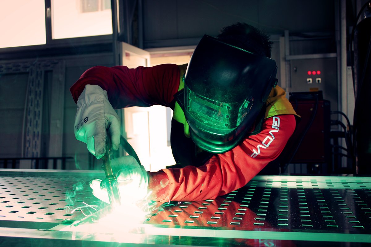 Welder joining a steel panel, arc light and sparks
